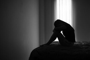 Silhouette of depressed woman sitting in bedroom Beset by health problems accumulated stress...