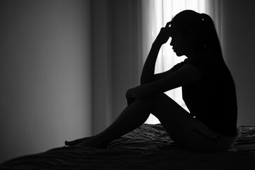 Silhouette of depressed woman sitting in bedroom Beset by health problems accumulated stress...