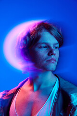 Portrait of calm, handsome man with freckles posing in vivid neon digital multicolored light and...