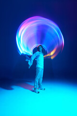 Full-length portrait of attractive young man posing in vivid blue neon light illuminating...