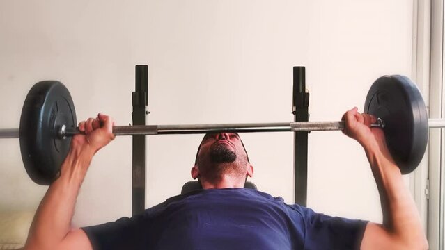 Young man lifting weights at home.