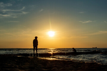 Sunset at sea with people on breakwater
