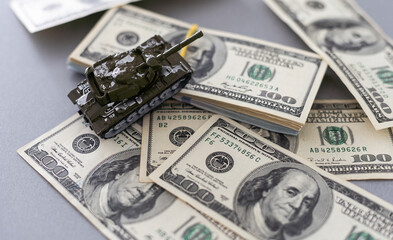 toy tank on the background of dollar bills