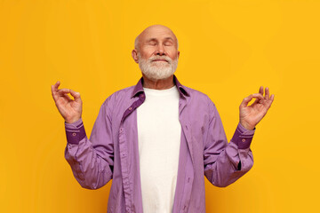 calm old bald grandfather in purple shirt meditates and does yoga on yellow isolated background