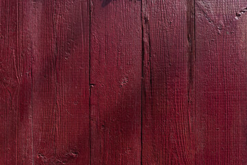 The old wooden surface is painted with red oil paint. Close-up. Texture. Abstract background