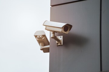 Outdoor security camera with a waterproof cover is installed on the exterior of a modern house, as...