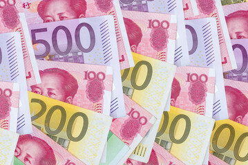 yuan and Euro banknotes on wooden background.