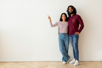 Happy young indian couple buying new house. pointing copy space