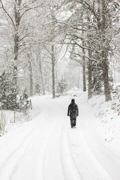 Woman walking in snow along country road