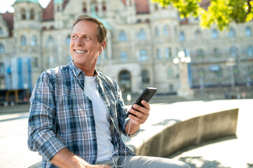 Man enjoying sightseeing in new city smiling happily using mobile phone.