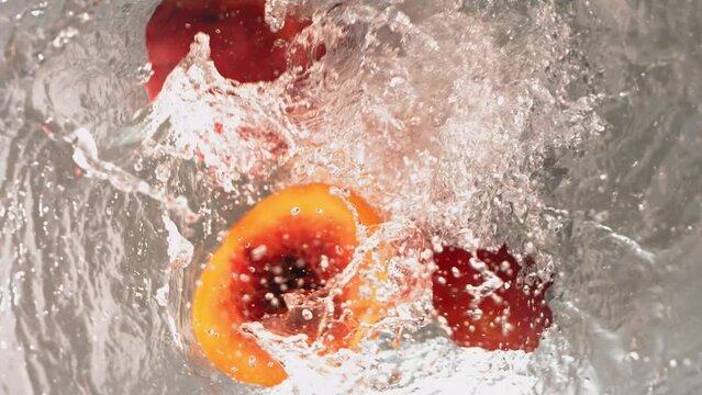 Super Slow Motion Shot of Fresh Peaches Falling into Water Whirl