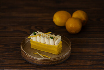 Lemon cake with whipped cream and yellow chocolate on a wooden table.
