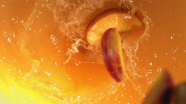 Super Slow Motion Shot of Fresh Peaches Falling into Juice Whirl