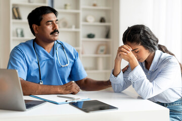 Indian Therapist Man Comforting Upset Female Patient During Meeting In Clinic - obrazy, fototapety, plakaty