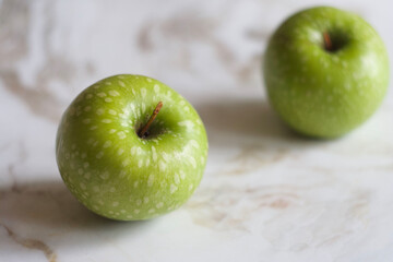 Green apples lie on a marble table
