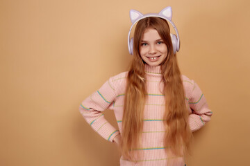 Smiling little girl in headphones with ears on beige background
