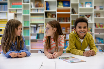 School kids sitting at desk in school library.