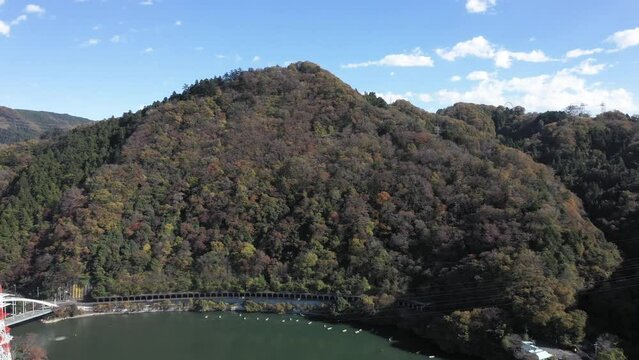 秋の色づく山々、紅葉などのイメージに　相模湖のドローン映像道路入りの動画