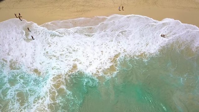 Top view of beautiful sand beach with azure seawater, Wave propagation, aerial shot from drone camera. People walking on the beach. 4k footage. Traveling. Kelingking Beach Nusa Penida, Indonesia