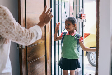 School girl with backpack waving goodbye to her parent before going to school - obrazy, fototapety, plakaty