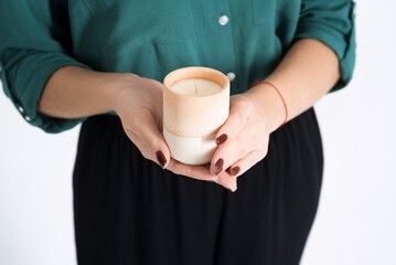 Close-up of women's hands with candles. The woman recommends handmade candles isolated on a white studio background. Advertising handmade candles. Copy space