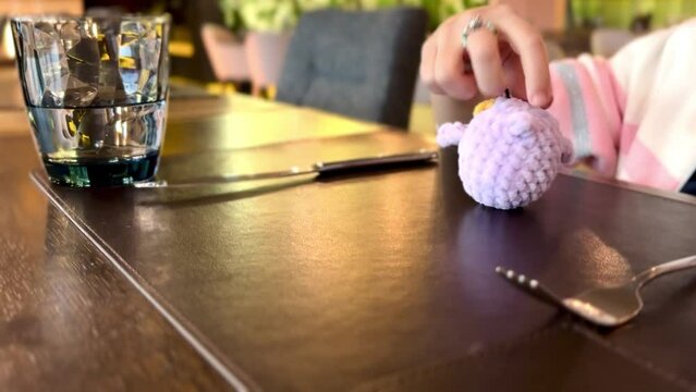 a little girl at the dinner table plays with a soft toy penguin, waits for the waiter in the restaurant to bring lunch. High quality HD footage