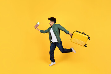 Excited young guy with luggage and passport running on yellow