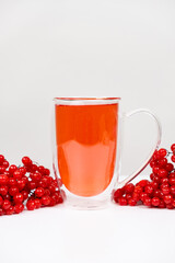 Hot viburnum tea in a glass cup with a double bottom on a white background.