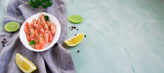 Boiled delicious shrimp with lemon and lime on marble background. Granite background. Selective focus.