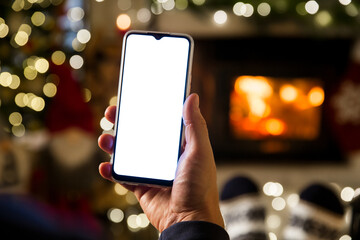 Unrecognizable Man Hands Using smartphone by fireplace at home, white blank empty screen display....