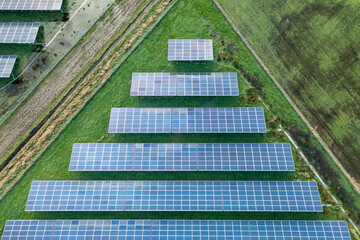 Field with several rows of solar panels, in the style of symmetrical compositions. Aerial view of...
