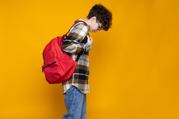 Curly teenager with a briefcase, on a yellow background.
