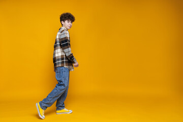Fototapeta na wymiar Attractive, curly boy teenager on a yellow background.
