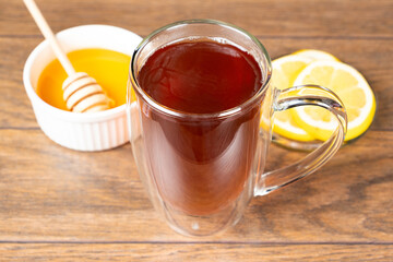 Black tea in a double-bottomed glass cup with lemon and honey. Tea for colds.