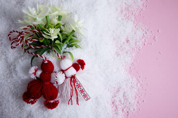 Martenitsa, Martisor with flowers in the snow on a pink background flat lay copy space