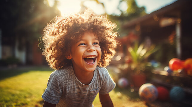 Portrait of a cute little boy with curly hair laughing outdoors.