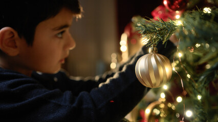 kid putting Christmas ball on the tree