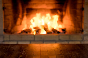 Empty old wooden table against burning wood in the fireplace