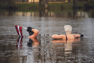 Couple ice bathing in the cold water of a lake in Preili, Latvia on the independence day. Wim Hof...