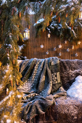 Christmas decoration in the backyard: a snowy swing with pillows and a cover, decorated with a pine garland with cones and toys