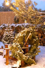 A large Christmas pine wreath near a wooden chair in the backyard...