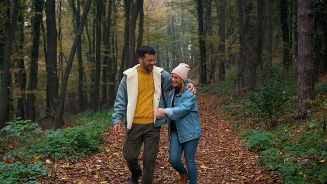 Portrait of couple spending time together walking in forest at morning.