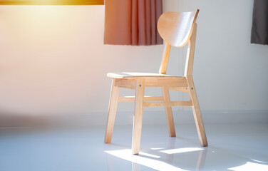 Elegant wooden chair in an empty room on the white marble floor with natural light from the window.