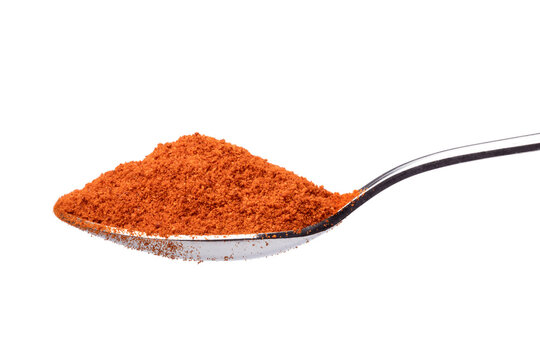 Metal spoon with ground red pepper paprika powder close up on white background