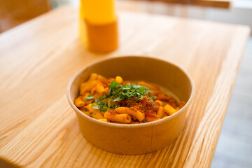 Penne pasta in tomato sauce with chicken, tomatoes decorated with parsley on a wooden background at cafe. High quality photo