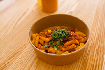 Penne pasta in tomato sauce with chicken, tomatoes decorated with parsley on a wooden background at cafe. High quality photo