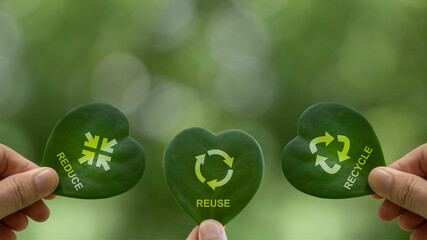 Hand holding green leaf with reduce, reuse, recycle symbol on green bokeh background. Ecological...