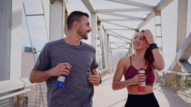 Young adult sport couple training fitness outdoors. Coach man and athlete woman jogging or running together with sport wear and smiling. Active friends doing healthy cardio exercise. Slow motion