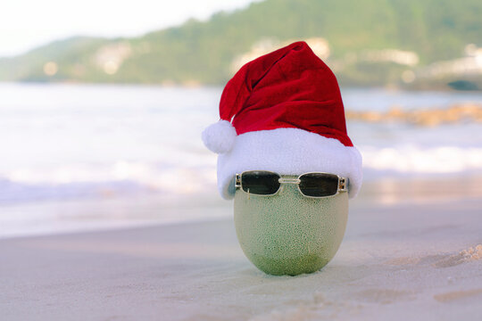 Funny looking Santa Claus cantaloupe Wear stylish sunglasses on the sand that contrasts with the sea. wearing a christmas hat Christmas and New Year holiday ideas on the beach, Patong, Phuket, 