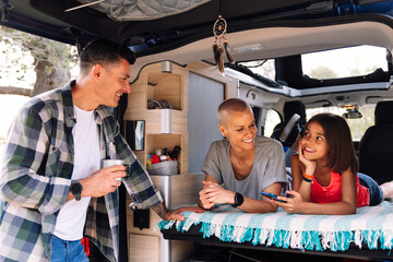 family relaxing lying in the back of their camper van, concept of active tourism in nature and outdoor activities with children